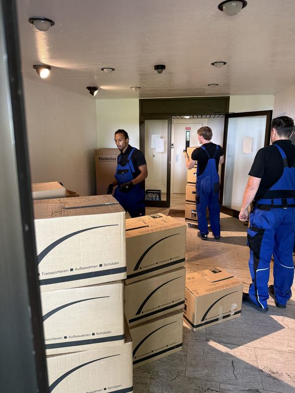Im Flur stellen mehrere Mitarbeiter Umzugskartons bereit