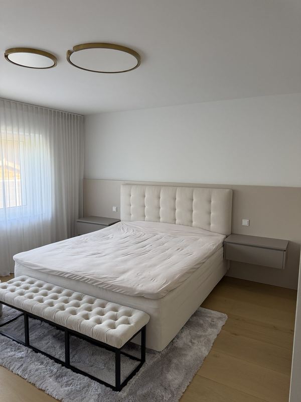 Helles Schlafzimmer mit aufgebautem Boxspringbett und einer Sitzbank am Fußende