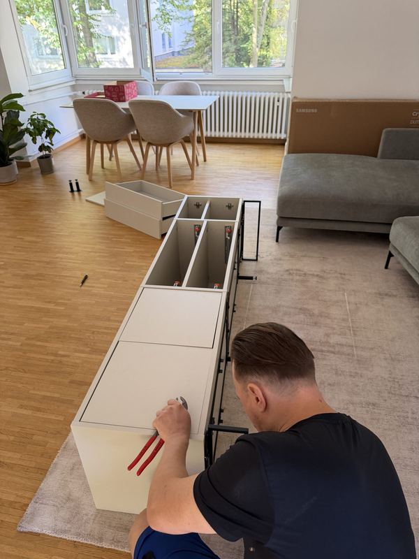 Von oben gesehen: Ein Mitarbeiter arbeitet an den Schubladenauszügen eines liegenden Sideboards