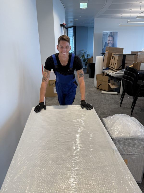 Ein Mitarbeiter hinter einer Tischplatte, die großflächig in Luftpolsterfolie eingepackt ist